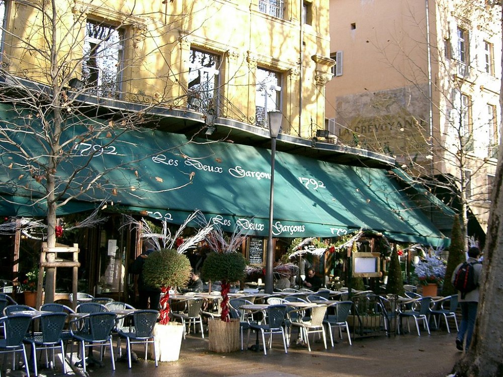 Café Les deux garçons à Aix-en-Provence : Terrasse de la brasserie à laquelle reste attaché le souvenir de la jeunesse de Zola et de Cézanne. (Crédit photo : PRA sur Wikipédia)